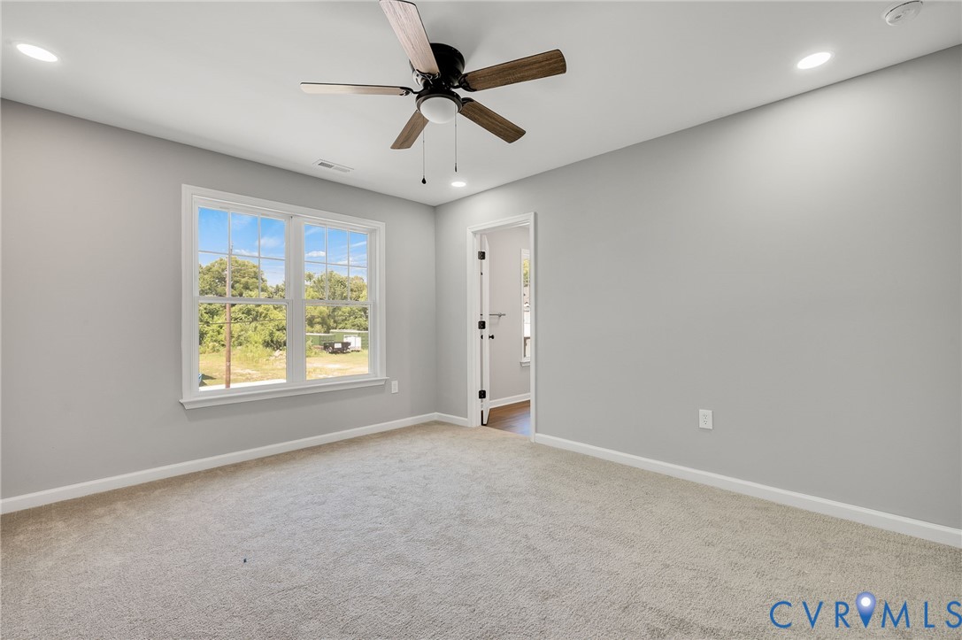 Interior space featuring neutral wall tones, plush wall-to-wall carpeting, recessed ceiling lighting, and a multi-blade ceiling fan with integrated light fixture