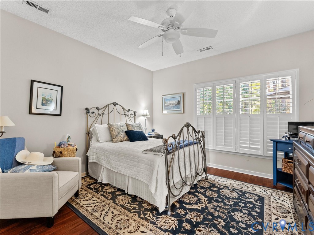 Interior space featuring wood-finish flooring, multi-pane window with white plantation shutters, and a ceiling fan with integrated lighting