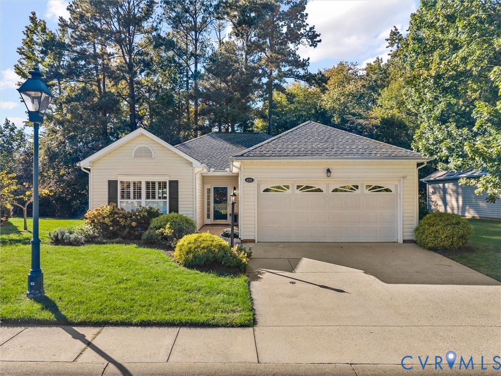 Single-story residence featuring light-colored siding, an attached two-car garage with arched decorative windows, a concrete driveway, and exterior lantern-style lighting