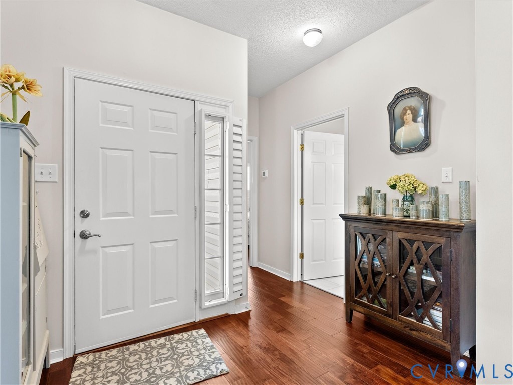 Entryway featuring wood-finish flooring, a six-panel front door with a sidelight, and flush-mount ceiling lighting