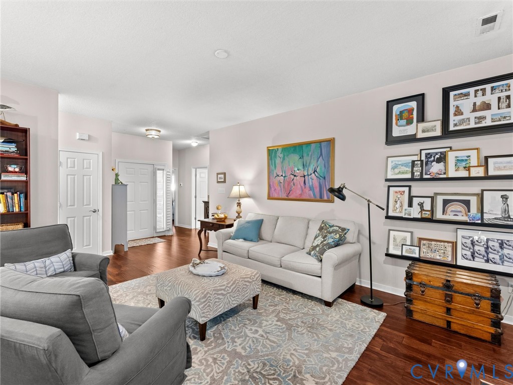 Living area featuring wood-finish flooring, high-contrast wall shelving, and a paneled entry door