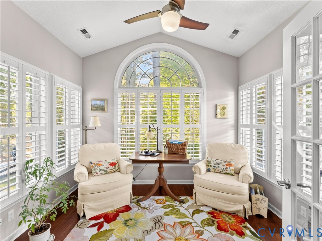 Sunroom featuring a vaulted ceiling, floor-to-ceiling arched window, plantation shutters, wood-finish flooring, and a ceiling fan with integrated lighting