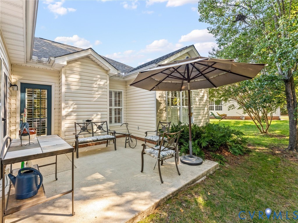Concrete patio featuring vinyl siding, exterior lighting, and multi-pane windows