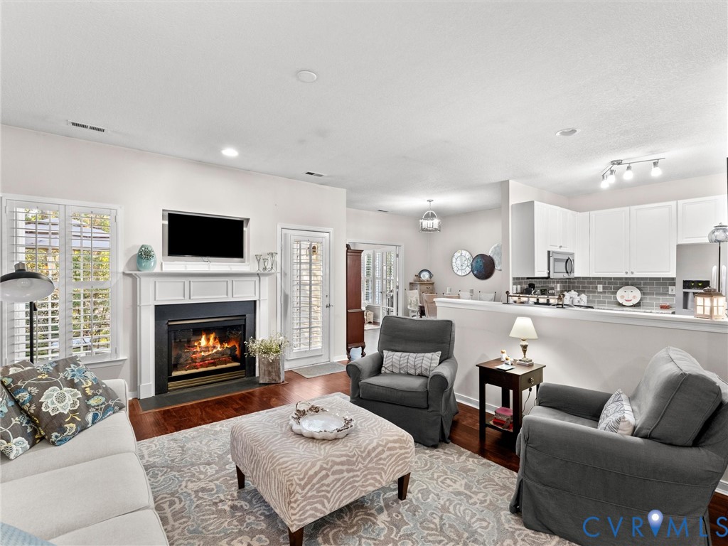 Fireplace with white mantle, wood-finish flooring, recessed lighting, and white cabinetry