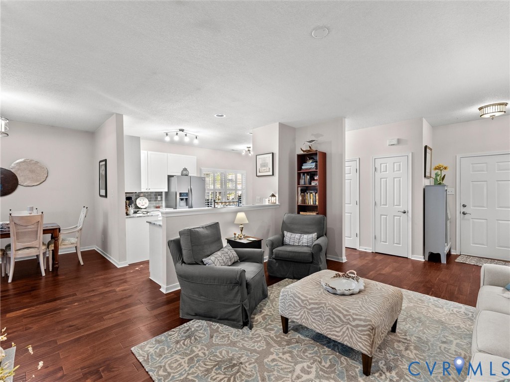 Open-concept interior featuring wood-finish flooring, recessed lighting, and a kitchen equipped with white cabinetry and stainless-steel appliances