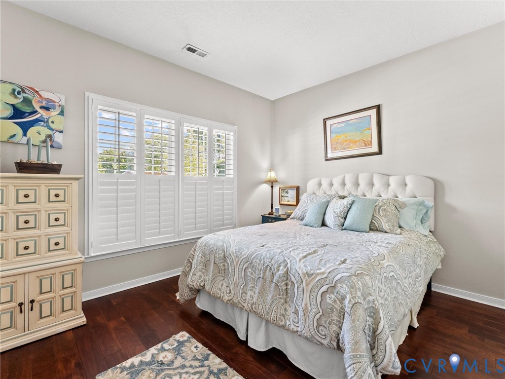 Room featuring wood-finish flooring, white plantation shutters, and neutral wall paint
