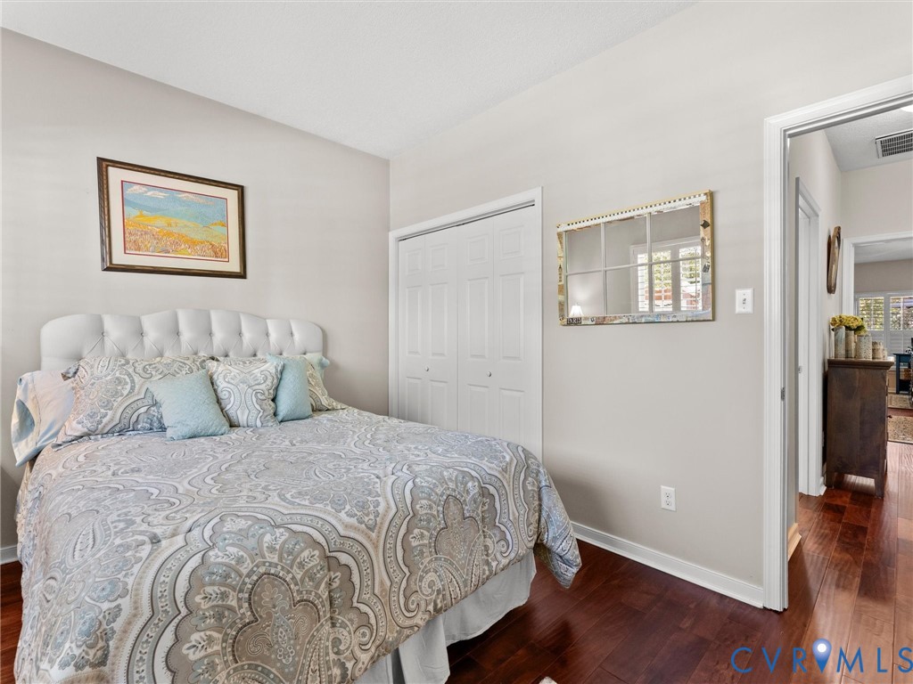 Room with wood-finish flooring, dual-panel closet doors, and neutral wall paint