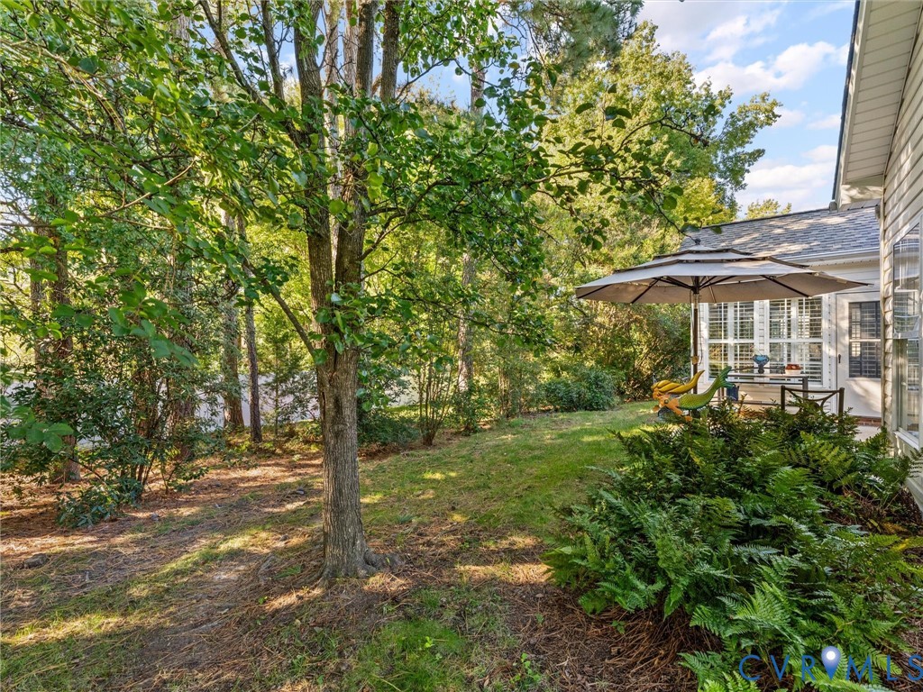 Private backyard featuring mature trees, landscaped shrubbery, grass lawn, and siding exterior