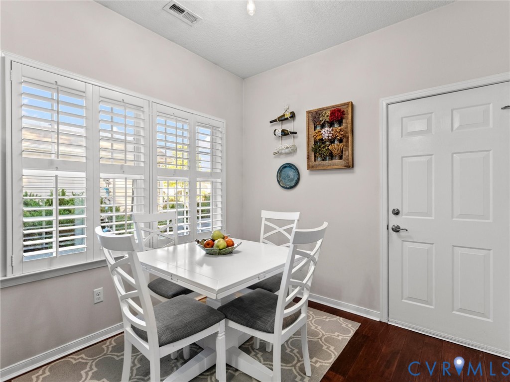 Room featuring wood-finish flooring, plantation shutters, and a six-panel door
