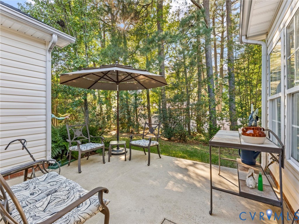 Concrete patio enclosed by light-colored vinyl siding with surrounding mature pine trees