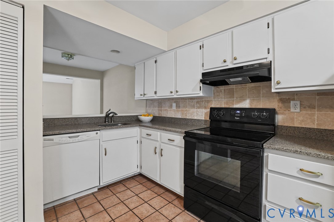 Kitchen featuring white cabinetry, stone-finish countertops, tiled backsplash, black range, and ceramic tile flooring