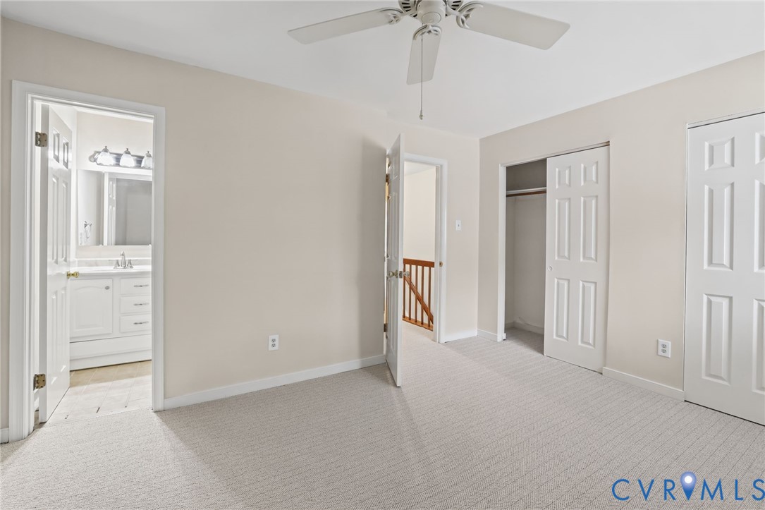 Neutral-toned interior space featuring wall-to-wall carpeting, a ceiling fan, and built-in closet storage with six-panel doors