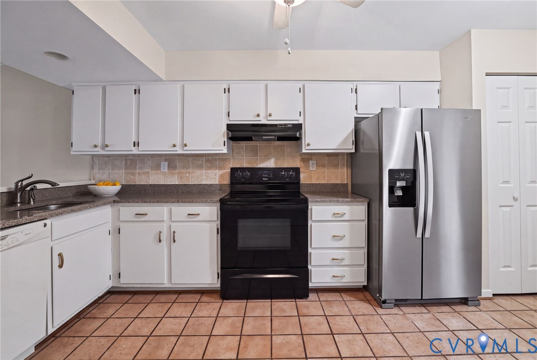 Kitchen featuring white cabinetry, solid-surface countertops, stone-tile backsplash, ceramic-tile flooring, and stainless steel side-by-side refrigerator