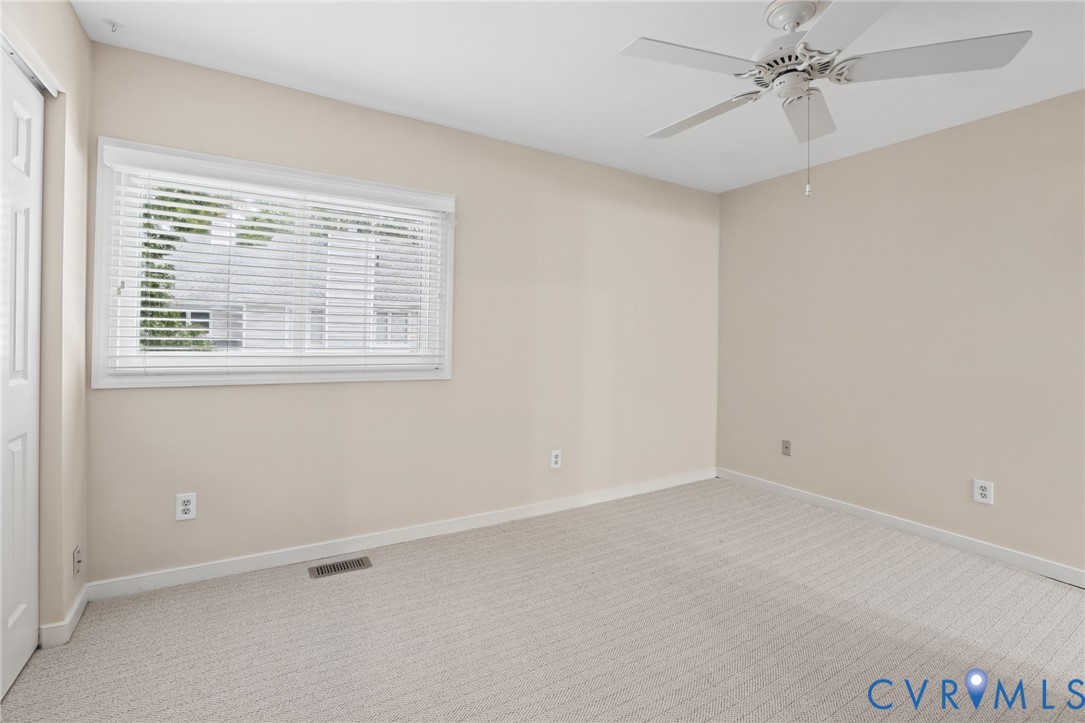 Neutral-toned interior featuring wall-to-wall carpeting, ceiling-mounted paddle fan, and horizontal slat window blinds