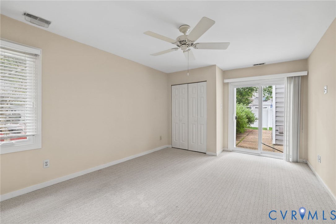 Room featuring neutral carpeting, a ceiling fan, closet with double doors, and a sliding glass door providing external access