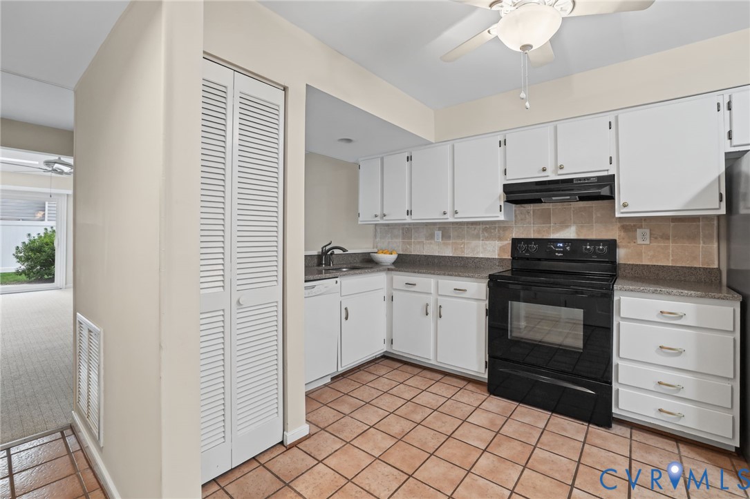 Kitchen featuring white cabinetry, stone-finish countertops, tiled backsplash, black range, and ceramic tile flooring