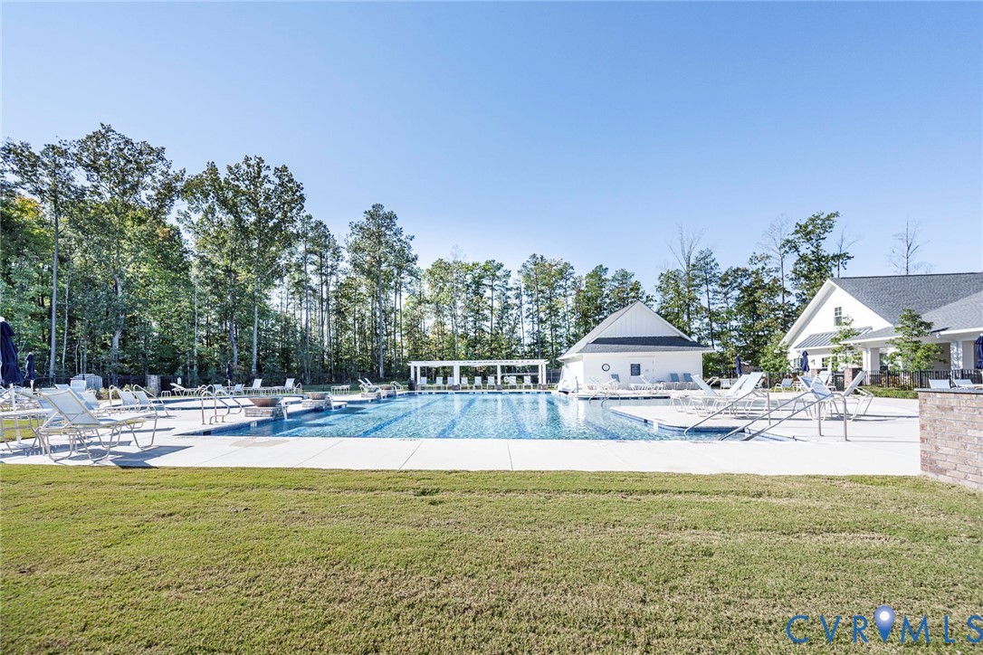 Outdoor swimming pool featuring a concrete deck, built-in lap lanes, pergola-covered lounge area, and expansive lawn