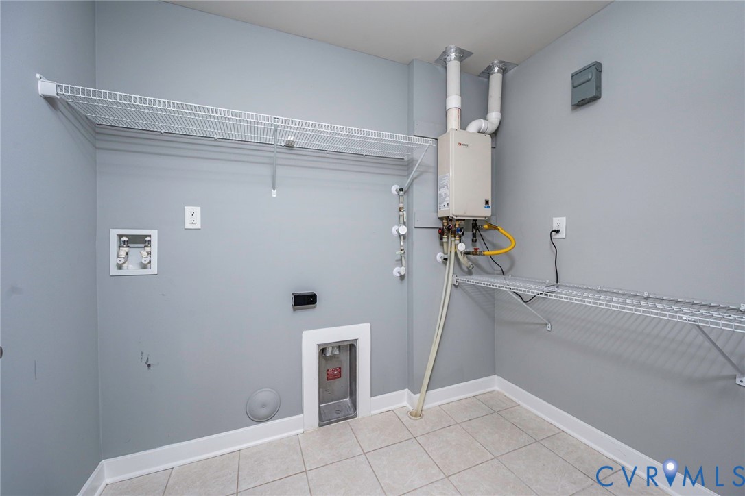 Utility room featuring tile flooring, washer dryer hookups, wall-mounted tankless water heater and shelving