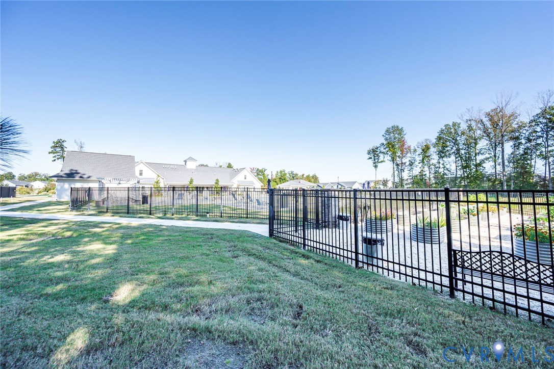 Fenced outdoor space featuring a graveled area, metal garden planters, and a concrete pathway