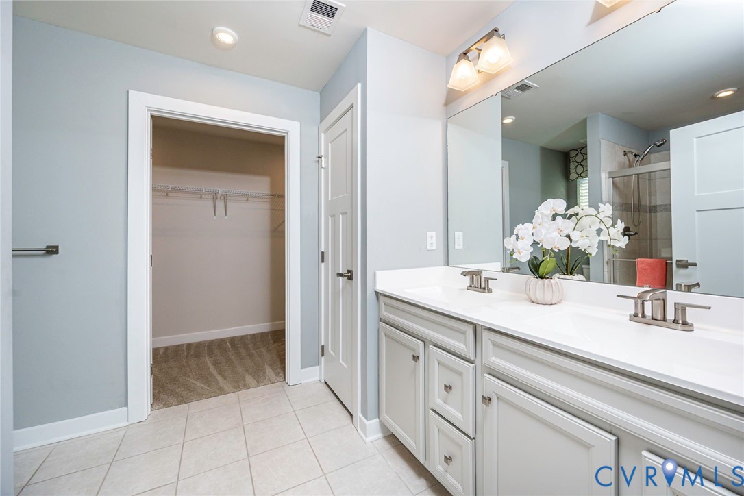 Primary Bedroom with Attached Bathroom with dual vanity,linen closet, tiled flooring and large walk-in closet