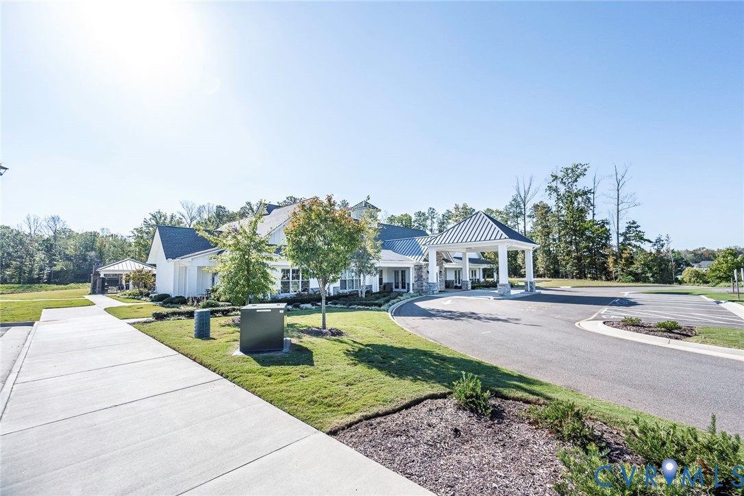 Exterior featuring a white facade, metal roof accents, covered porte-cochre, paved driveway, and professional landscaping