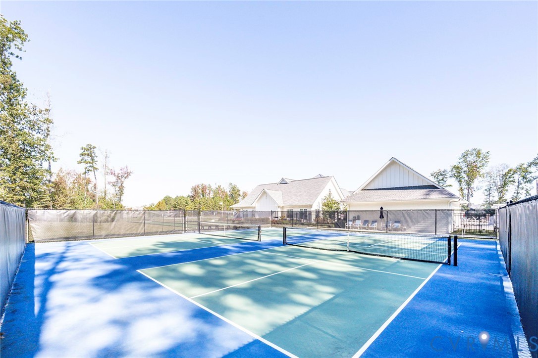 Hard-court sports surface enclosed by perimeter fencing and netting