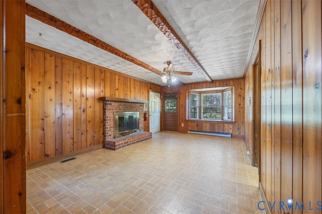 Paneled walls in den with wood burning fireplace and bay window create a cozy atmosphere. Paneled walls in den with wood burning fireplace and bay window create a cozy atmosphere.