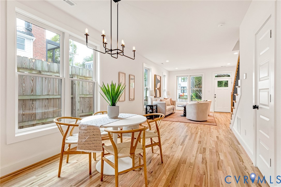 Open-concept living space featuring wood-finish flooring, multi-pane windows, recessed lighting, and a six-light candelabra chandelier