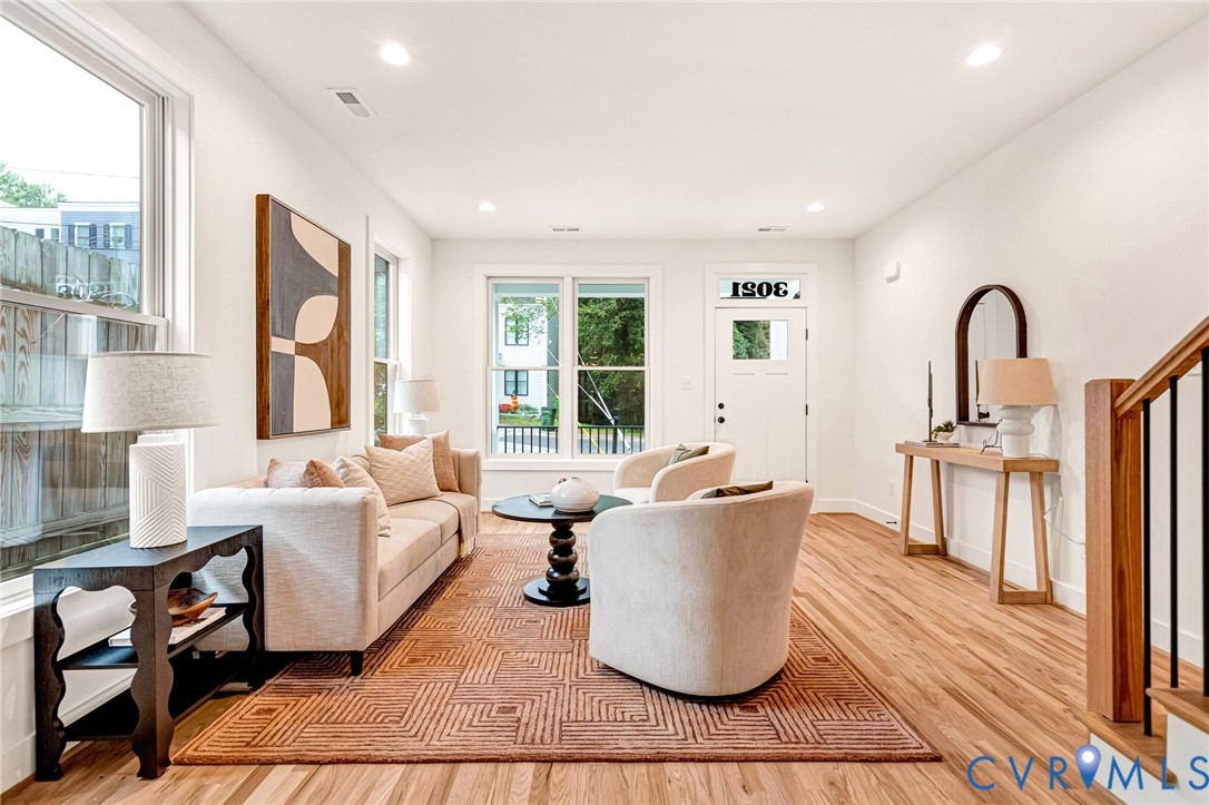 Interior space featuring wood-finish flooring, recessed lighting, double-hung windows, and a front entry door with a transom window