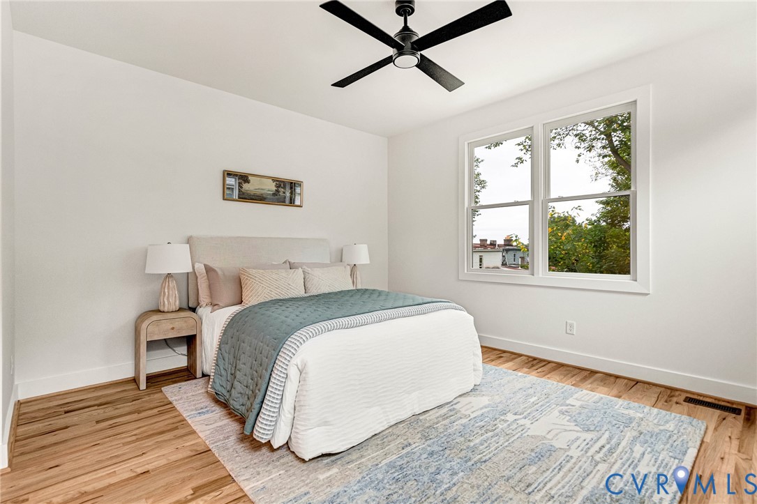 Interior space featuring wood-finish flooring, white walls, double-pane windows, and a matte black ceiling fan