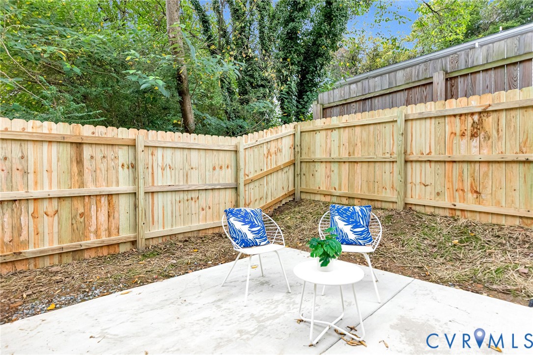 Concrete patio area enclosed by a wood privacy fence
