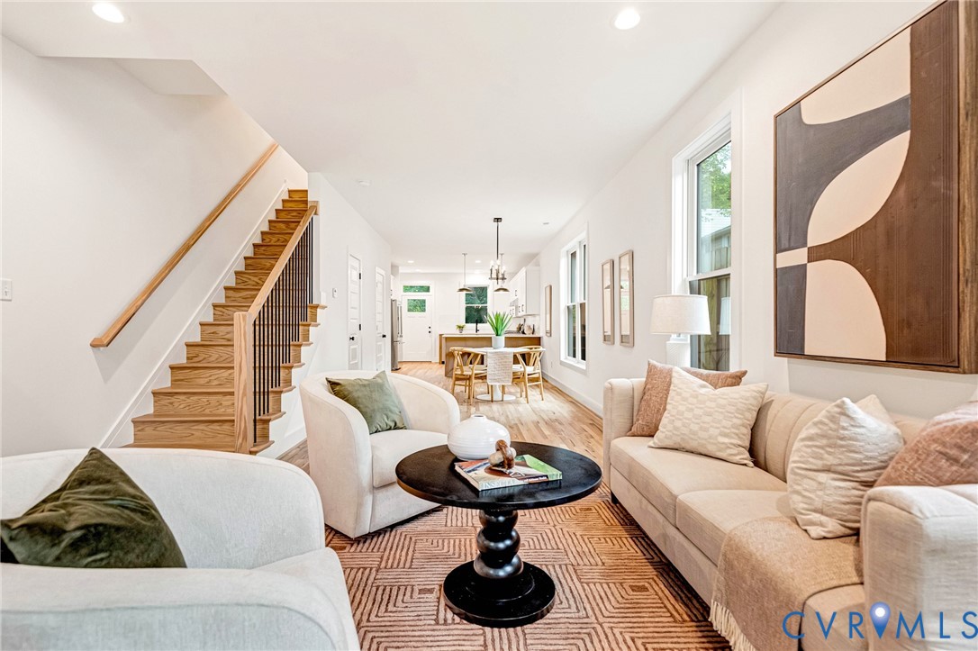 Open interior featuring wood-finish flooring, staircase with wood treads and metal balusters, recessed lighting, and multiple windows