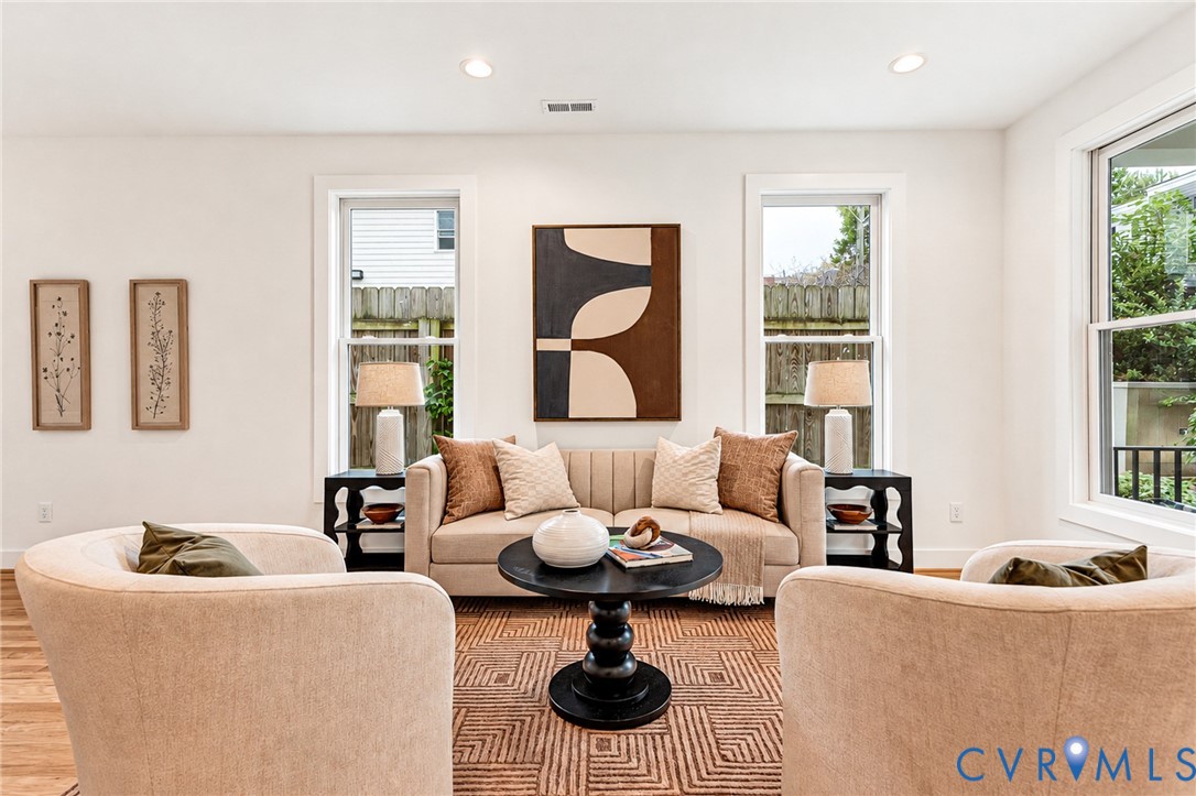 Neutral-toned interior featuring wood-finish flooring, recessed lighting, and multiple tall double-hung windows