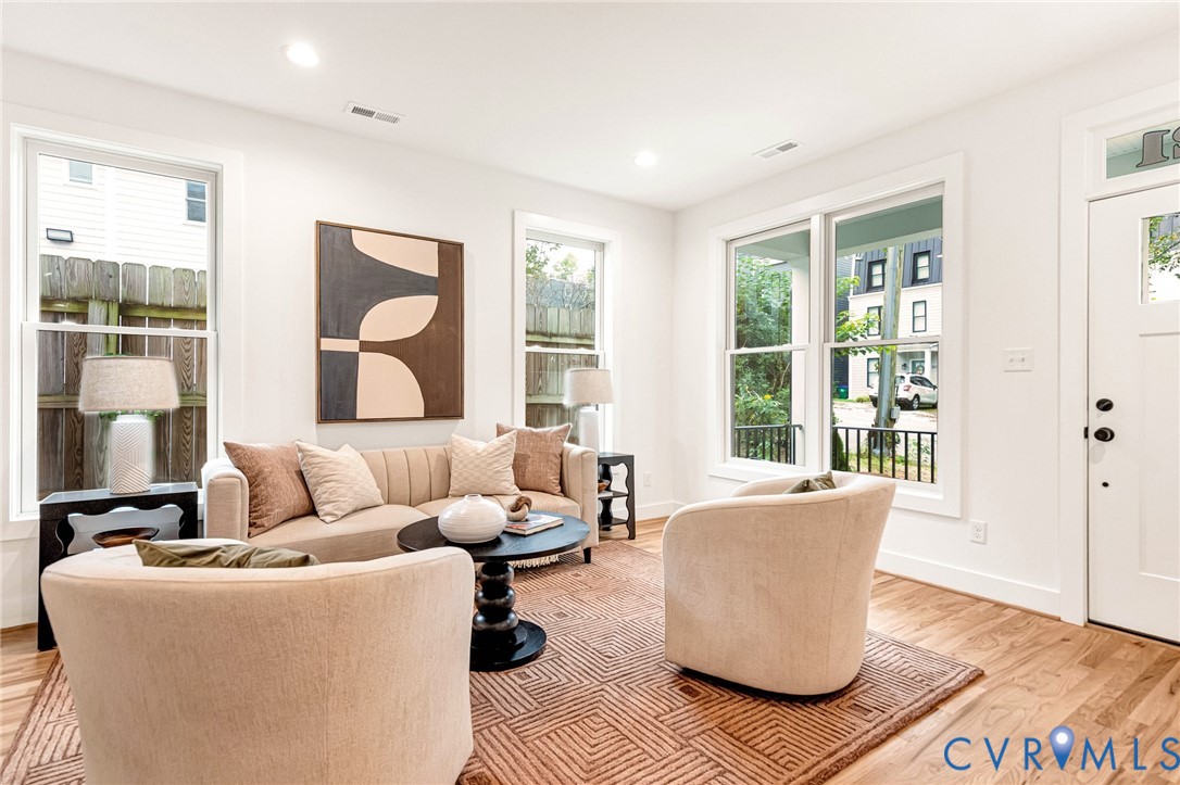 Living area featuring wood-finish flooring, recessed lighting, and multiple large windows with trim detailing