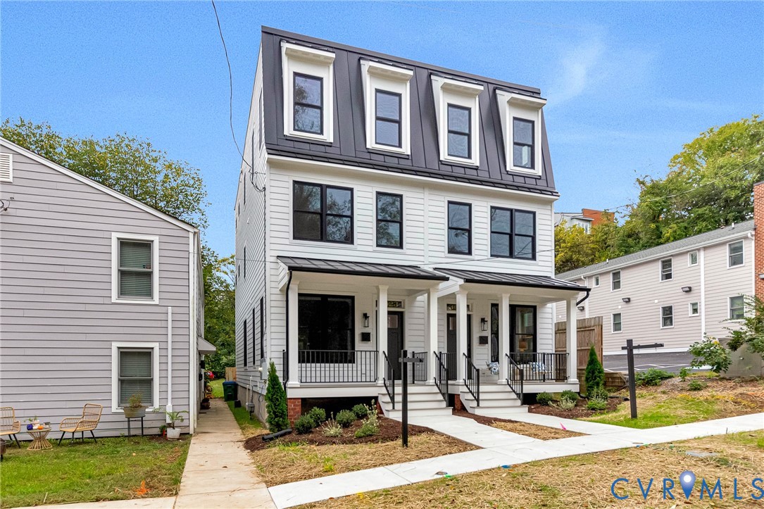Three-story townhouse featuring horizontal siding, a mansard roofline with dormer windows, metal roofing accents, and covered front porches with black metal railings
