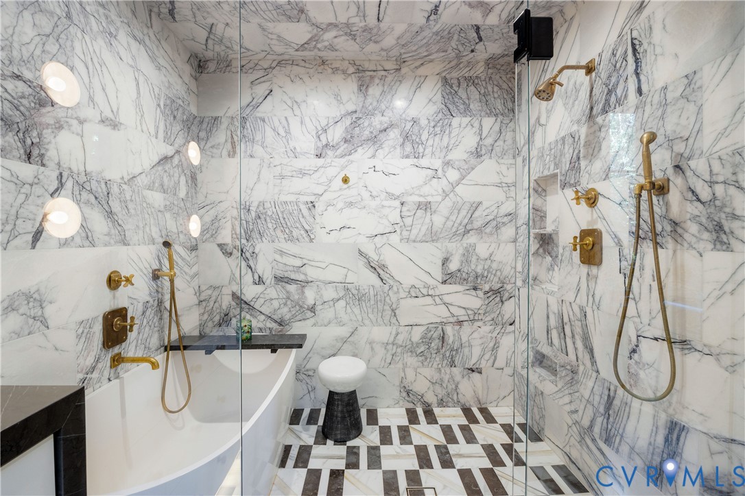 A glass-enclosed shower in lilac marble holds both the soaking tub and the shower, with Waterworks fittings and a heated floor.