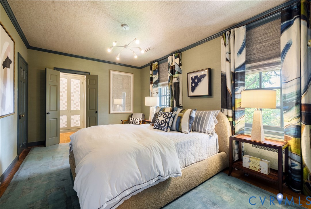 Bedroom with grasscloth walls and two closets.