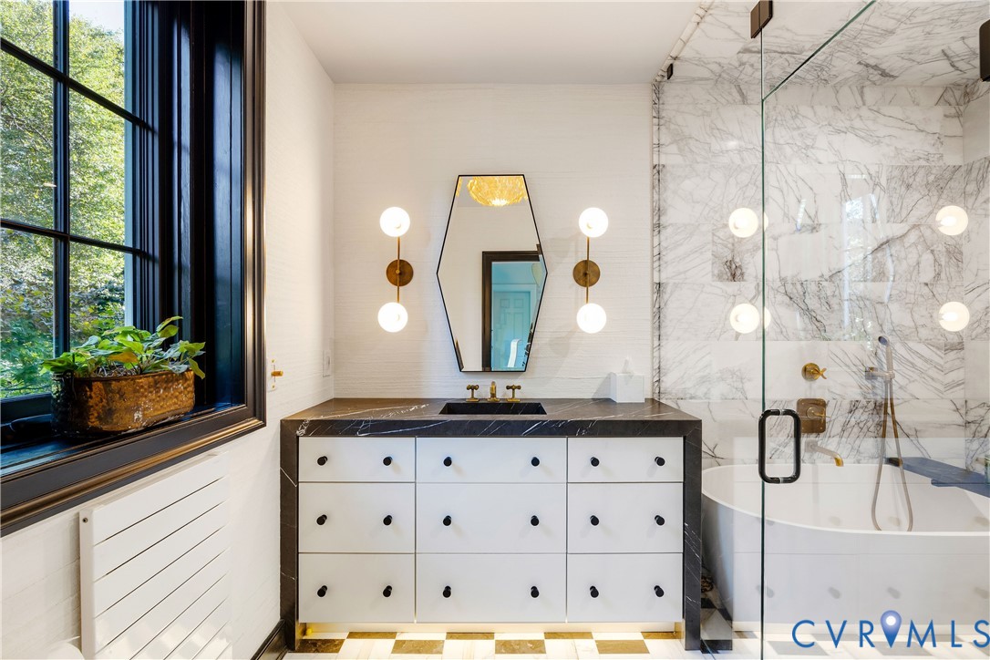 Bath beside the dressing room, with a custom vanity, waterfall marble top, soaking tub, integrated sink and toe-kick lighting.