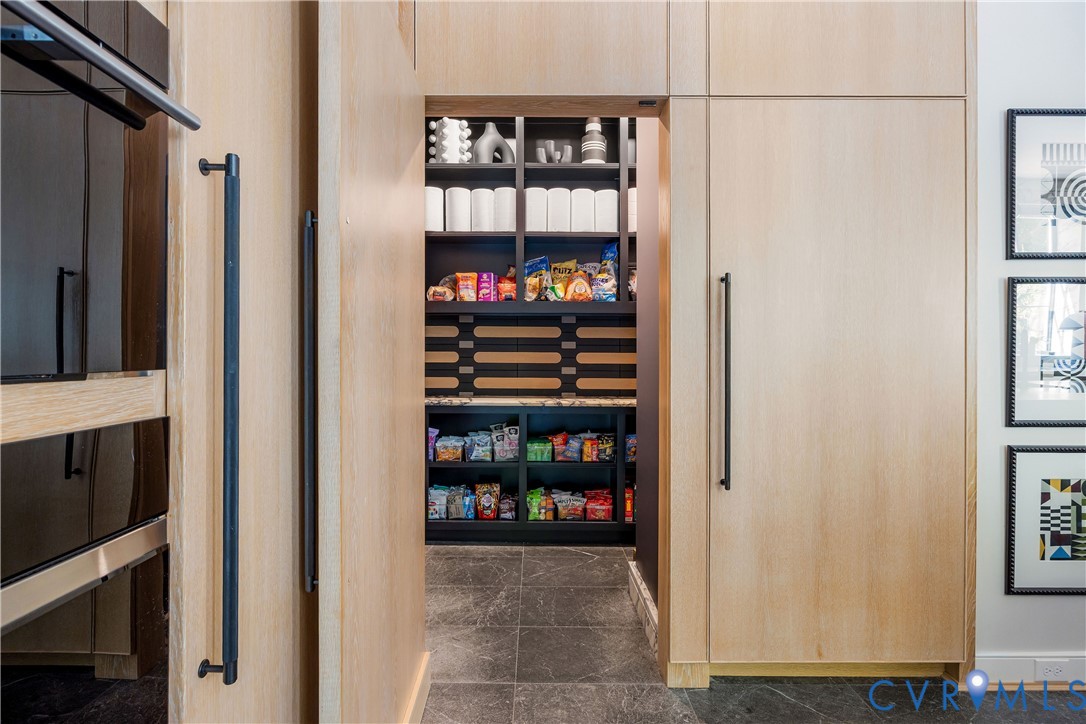Walk-in pantry behind flush white oak panels, with Calacatta Viola counters and baseboards and a Jamie Beckwith white oak backsplash.