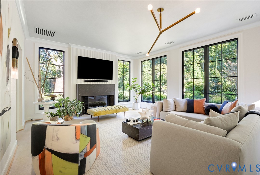 Family room with heated limestone floors, all new windows and its own HVAC, centered on a slatted fireplace wall with a custom marble mantel.