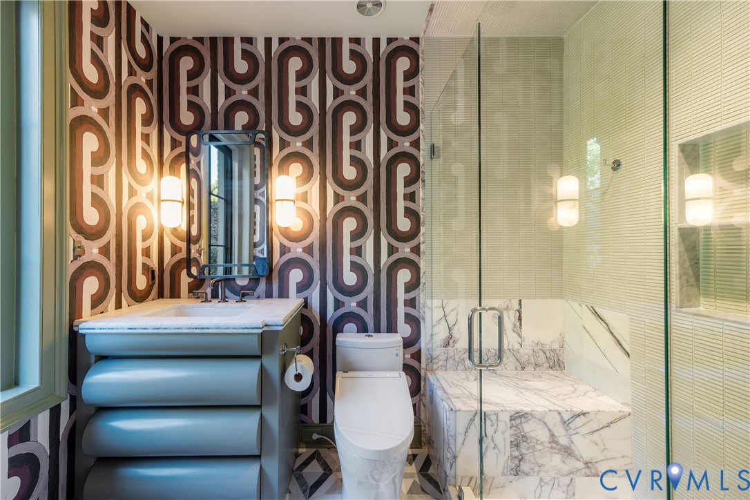 En suite bath with a custom vanity and marble shower with bench.