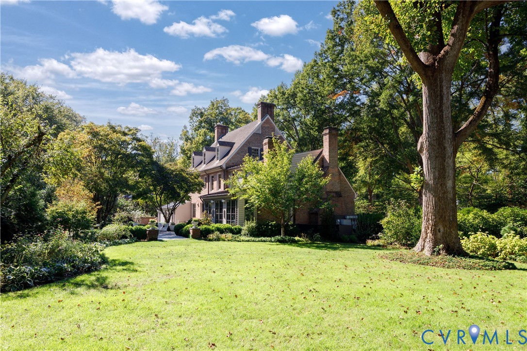 A wide side lawn shaded by mature trees, part of the 0.76-acre lot.
