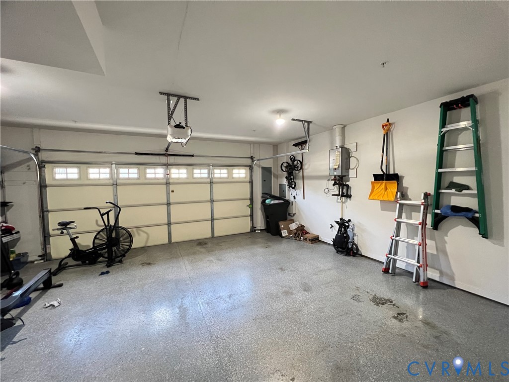 Two-car garage featuring a sectional door with windows, an epoxy-coated floor, and a wall-mounted tankless water heater Two-car garage featuring a sectional door with windows, an epoxy-coated floor, and a wall-mounted tankless water heater