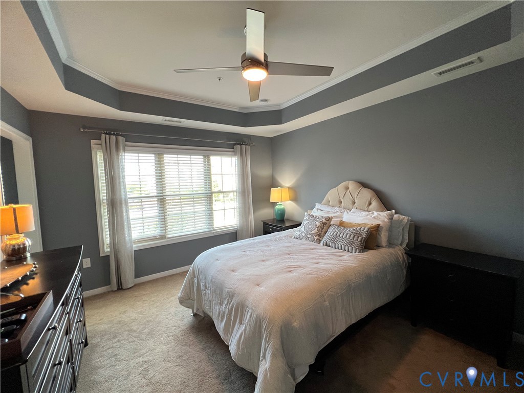 Tray ceiling featuring a central multi-blade ceiling fan with integrated lighting and multi-pane window configuration