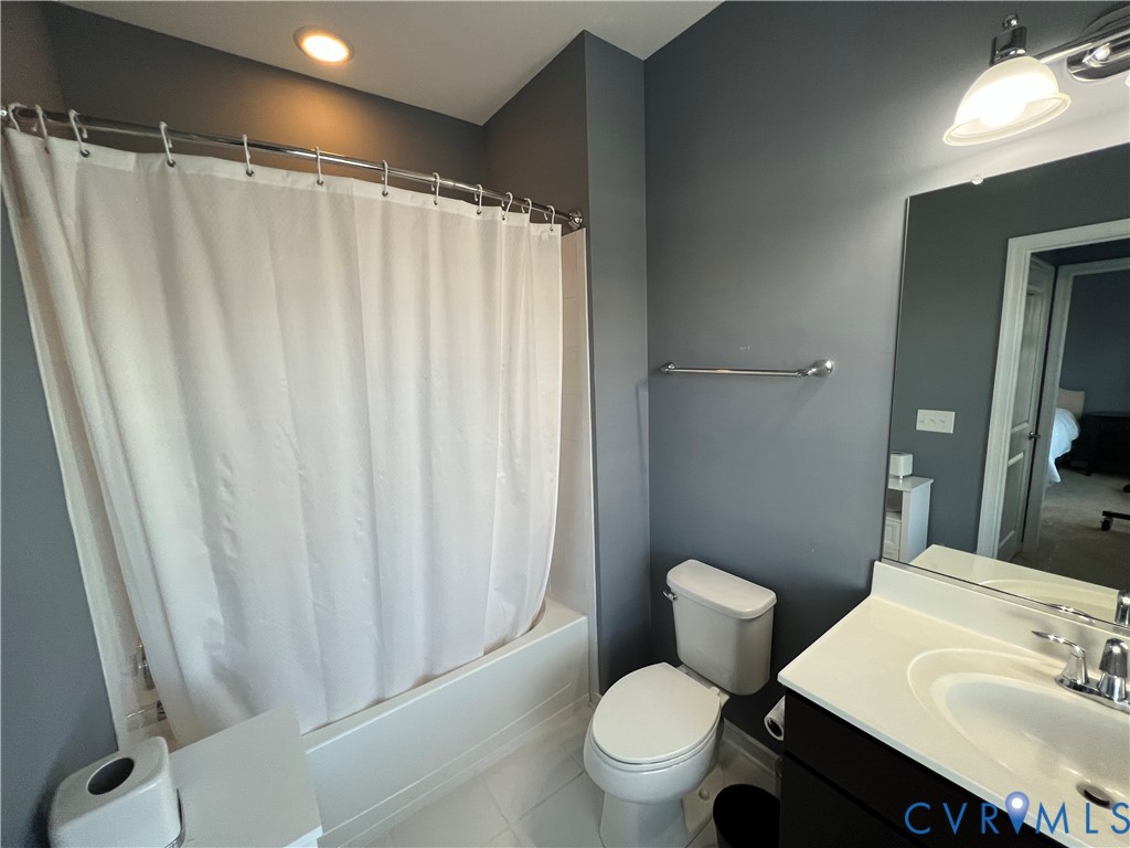 Bathroom featuring a tub-shower combination with surround, a vanity with a white countertop and integrated sink, a large wall-mounted mirror, and polished chrome hardware