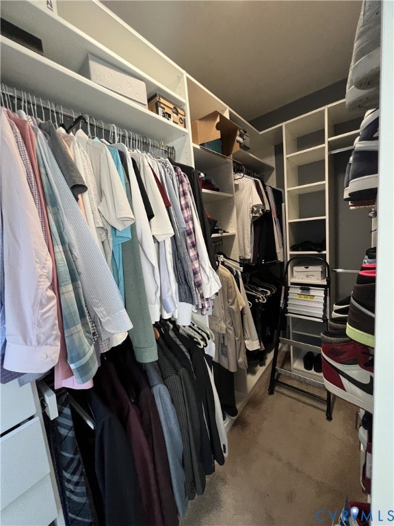 Walk-in closet featuring floor-to-ceiling white built-in shelving, multiple hanging rods, and integrated storage cubbies