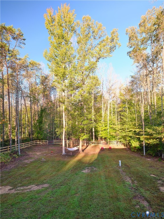 Expansive backyard featuring a level lawn, perimeter wood-post fencing, and mature trees