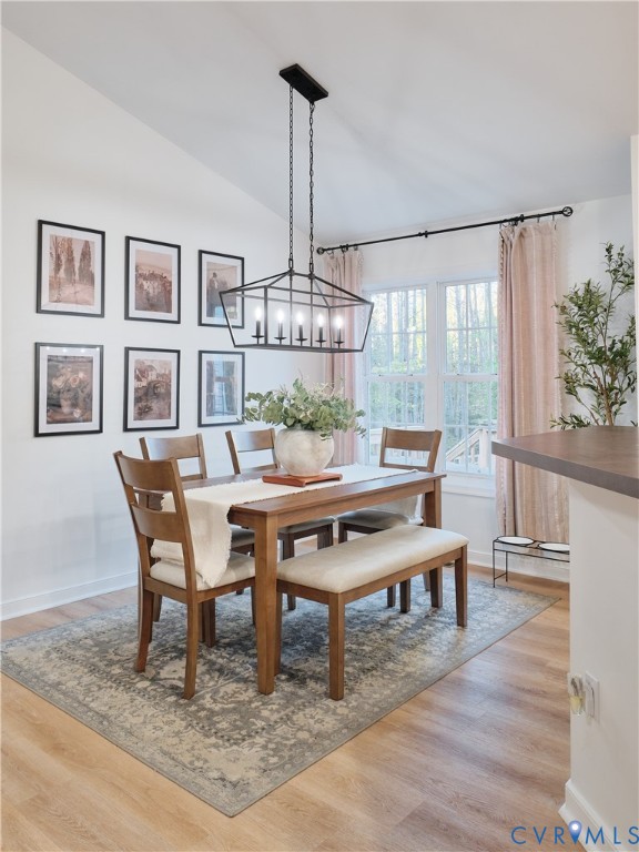 Dining area featuring vaulted ceilings, wood-finish flooring, and a multi-light geometric chandelier