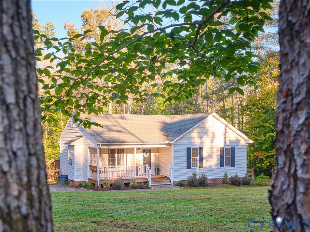 Single-story residence featuring light-colored siding, a covered front porch with white railing, brick foundation detailing, and dark shutters
