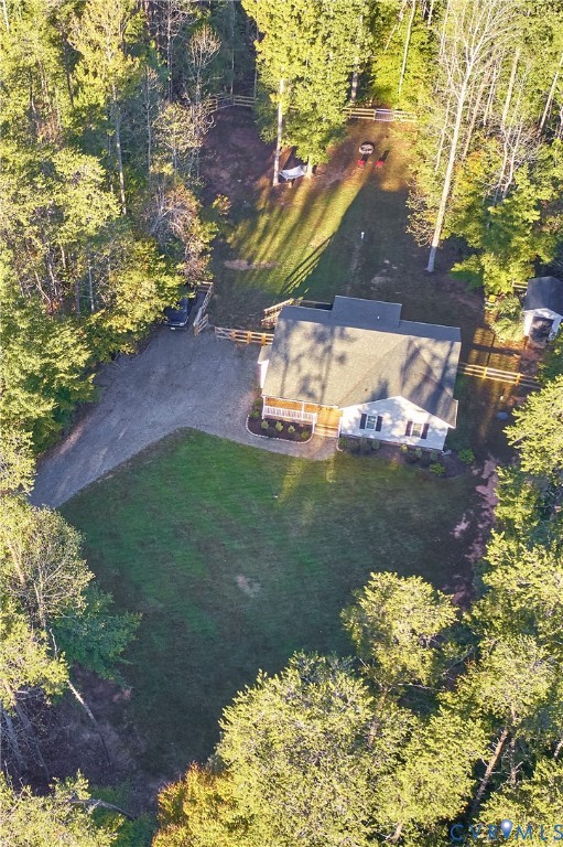 Expansive parcel featuring a wooded perimeter, gated entry, gravel driveway, and a residential structure with an asphalt shingle roof